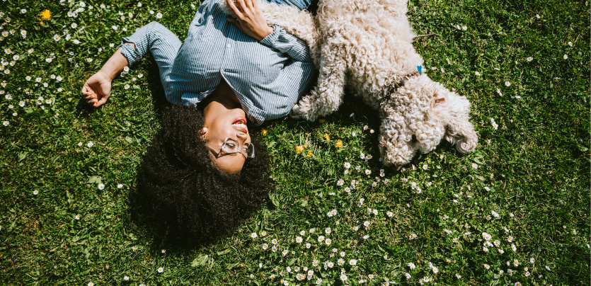 a dog and woman laying on grass