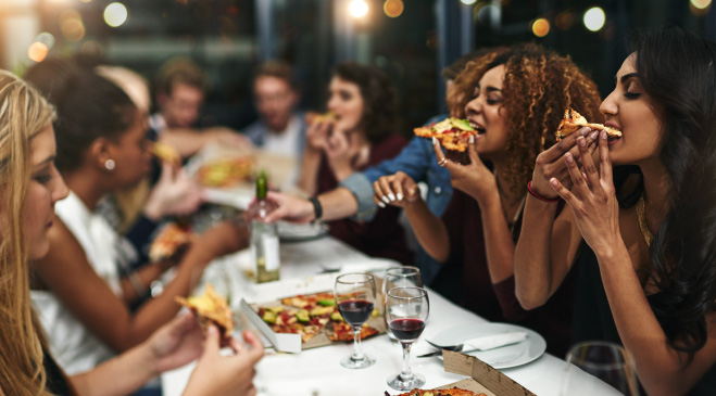 Friends eating pizza and drinking wine.